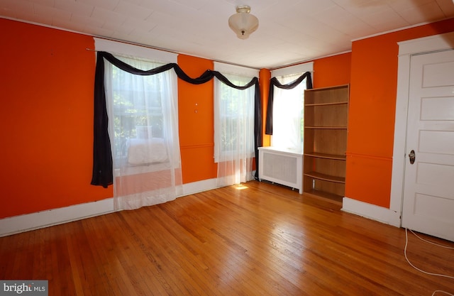 spare room featuring radiator heating unit, plenty of natural light, and wood-type flooring