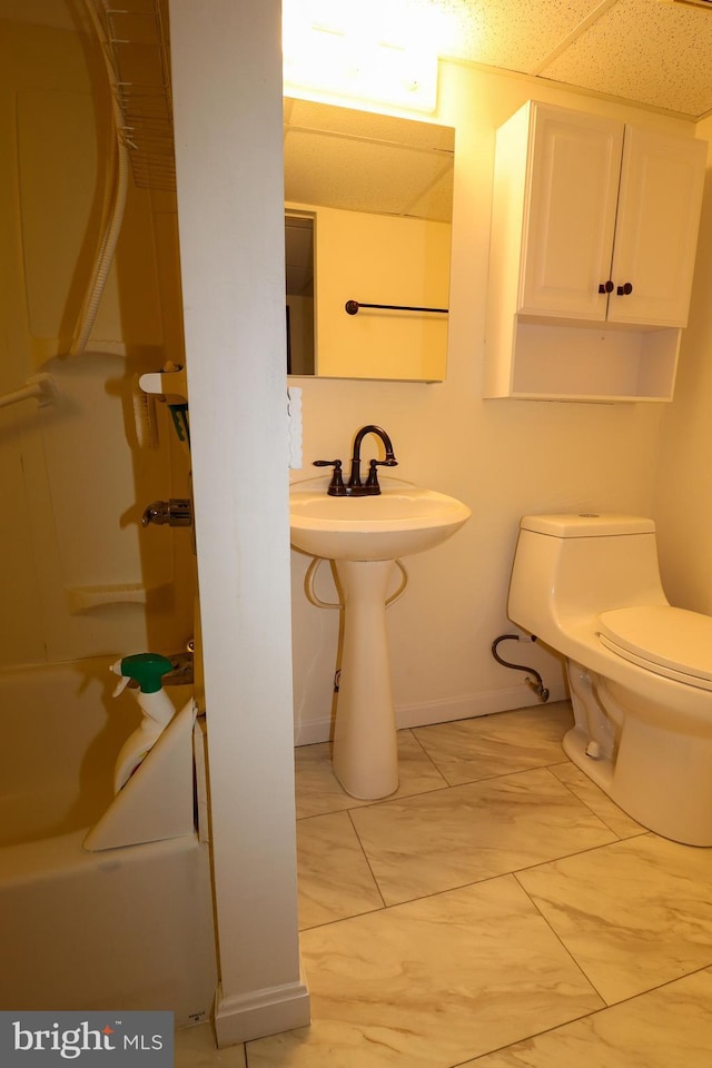 full bathroom with toilet, baseboards, and a sink
