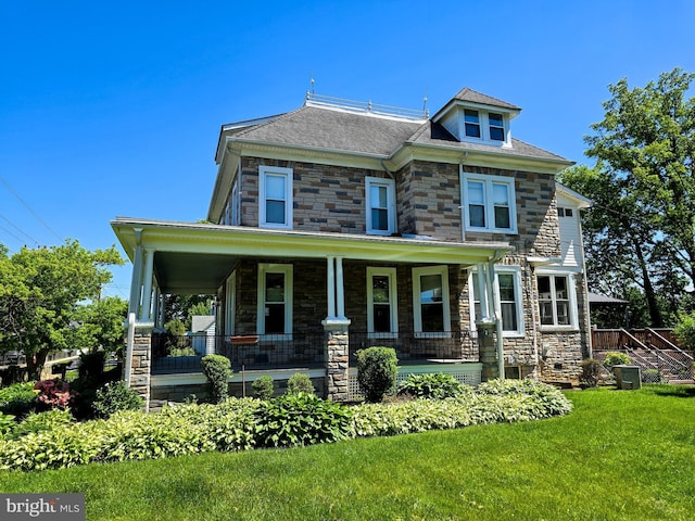 view of front of property with covered porch, a front yard, and stone siding