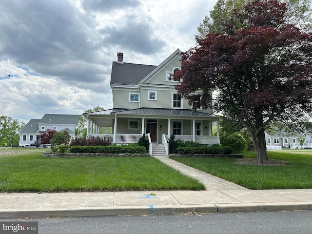 1303 Officers Row, Delaware City, DE 19706 - view of front facade featuring covered porch, a standing seam roof, a chimney, and a front lawn