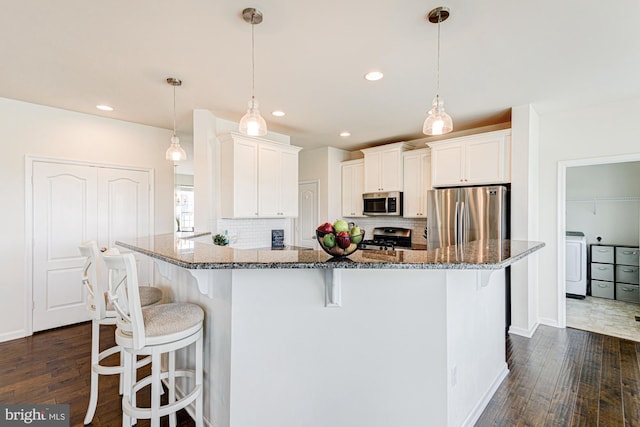 1303 Officers Row, Delaware City, DE 19706 - kitchen with appliances with stainless steel finishes, washer / dryer, a breakfast bar area, dark wood-style floors, and recessed lighting
