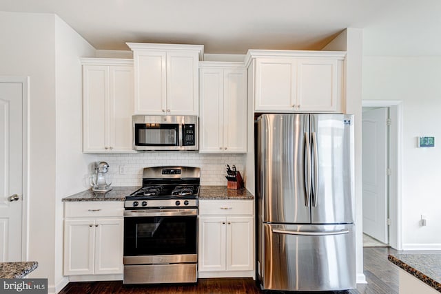 1303 Officers Row, Delaware City, DE 19706 - kitchen with stainless steel appliances, dark stone counters, white cabinetry, and decorative backsplash