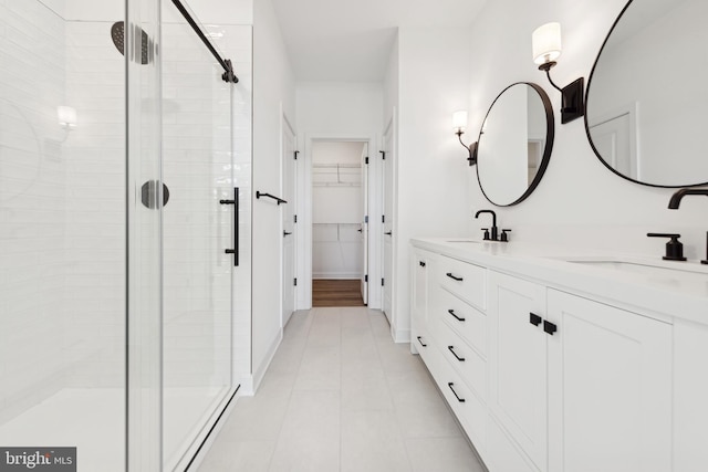 bathroom featuring a stall shower, double vanity, a walk in closet, and tile patterned floors