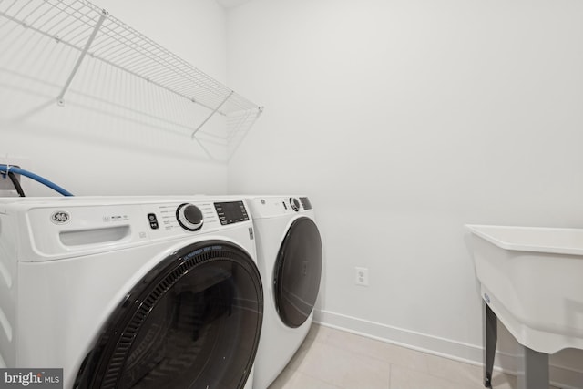 laundry room with washing machine and dryer, baseboards, and light tile patterned flooring