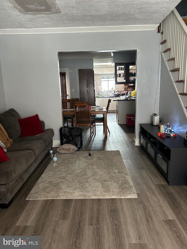 living area featuring ornamental molding, wood finished floors, stairs, and a textured ceiling