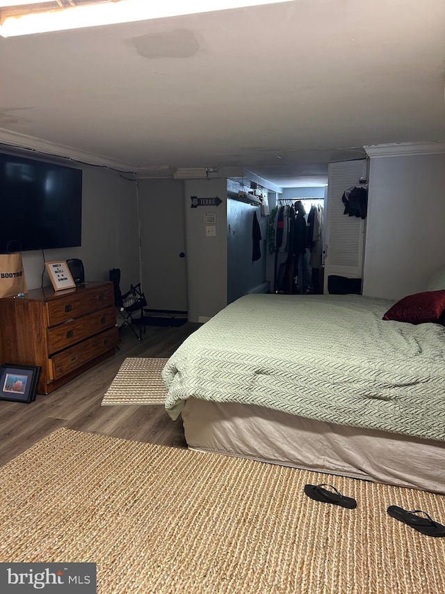 bedroom with ornamental molding and wood finished floors