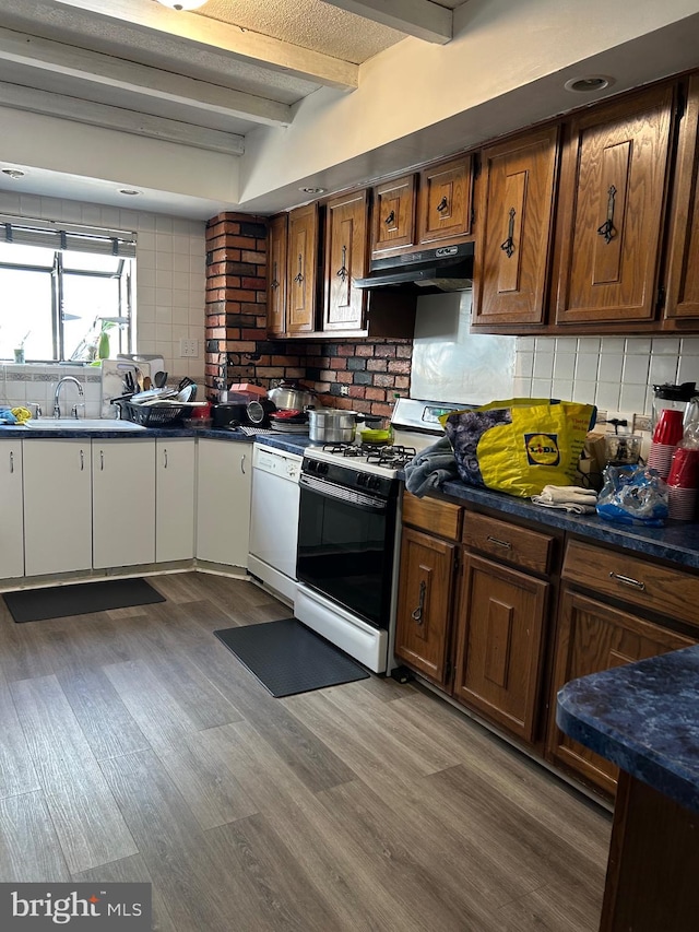 kitchen with dishwasher, gas stove, under cabinet range hood, decorative backsplash, and beam ceiling
