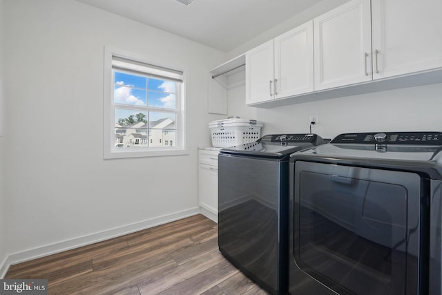 washroom with separate washer and dryer, cabinet space, wood finished floors, and baseboards