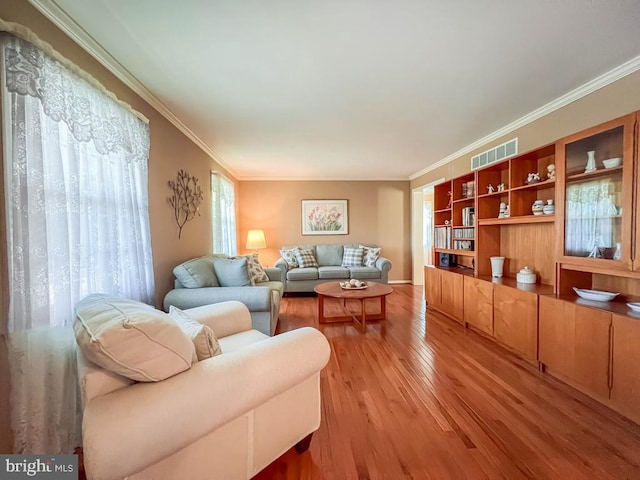 living area with ornamental molding and light wood-style flooring