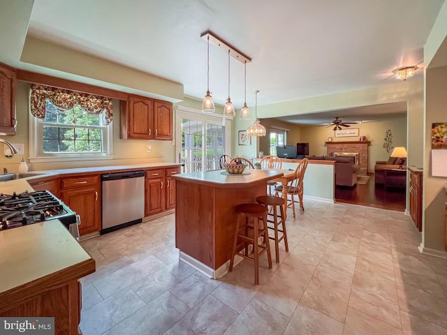 kitchen with appliances with stainless steel finishes, a sink, a brick fireplace, a breakfast bar, and open floor plan