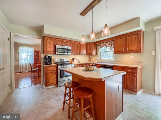 kitchen with stainless steel appliances, light countertops, brown cabinetry, and a kitchen island