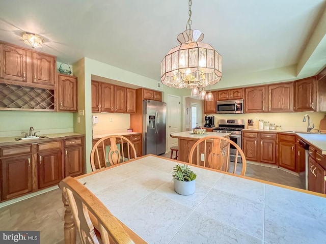 kitchen with appliances with stainless steel finishes, a sink, light countertops, and brown cabinets