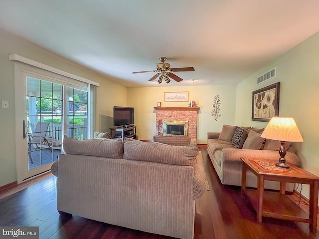 living room with dark wood-style flooring, ceiling fan, a fireplace, and baseboards