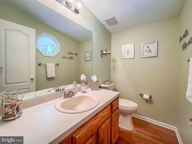 bathroom with wood finished floors, baseboards, toilet, and vanity