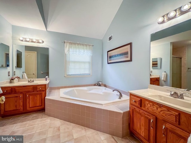 bathroom with tile patterned floors, a bath, lofted ceiling, a stall shower, and two vanities