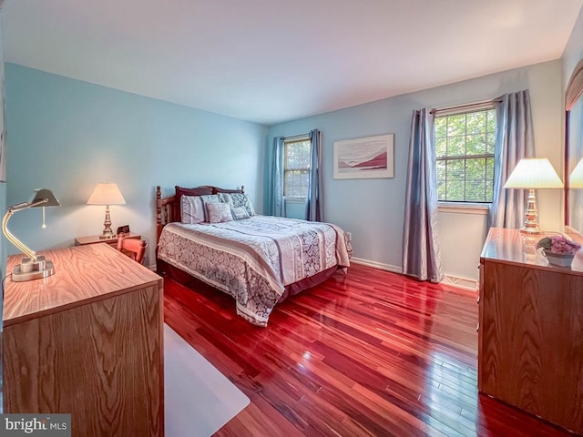 bedroom with multiple windows, wood finished floors, and baseboards