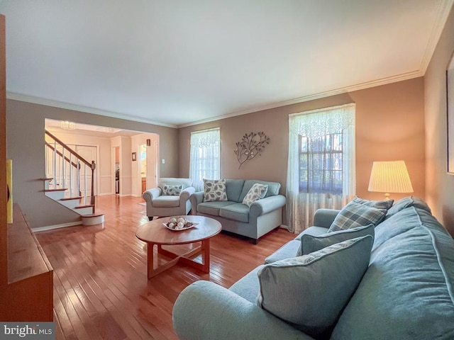 living room with wood-type flooring, ornamental molding, and stairs
