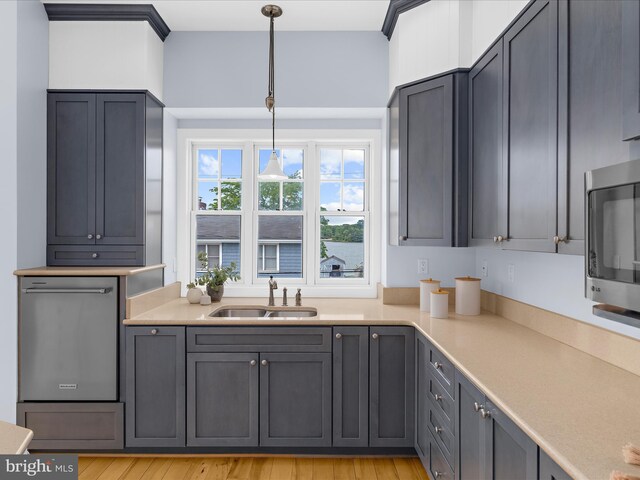 7839 Denton Ave, Baltimore, MD 21219 - kitchen featuring a sink, stainless steel appliances, light countertops, hanging light fixtures, and light wood finished floors
