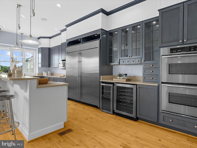 7839 Denton Ave, Baltimore, MD 21219 - kitchen featuring appliances with stainless steel finishes, beverage cooler, glass insert cabinets, decorative light fixtures, and crown molding