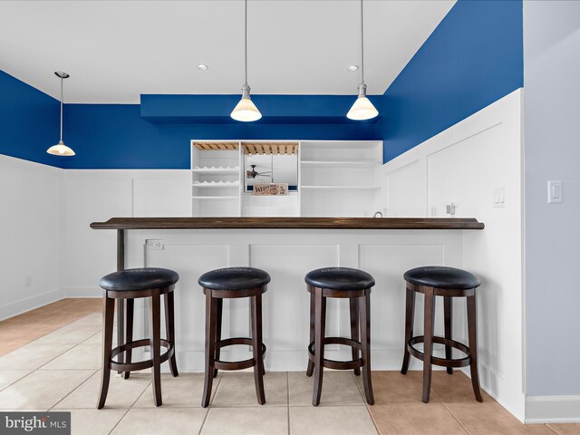 7839 Denton Ave, Baltimore, MD 21219 - kitchen featuring a decorative wall, pendant lighting, light tile patterned floors, and a breakfast bar