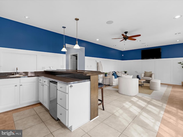 7839 Denton Ave, Baltimore, MD 21219 - kitchen with ceiling fan, a sink, white cabinetry, a breakfast bar area, and a decorative wall