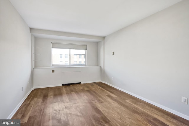empty room featuring wood finished floors and baseboards