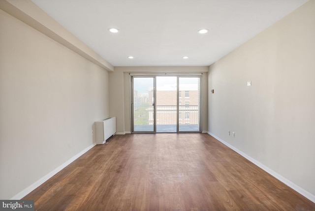 unfurnished room with radiator, baseboards, wood finished floors, and recessed lighting