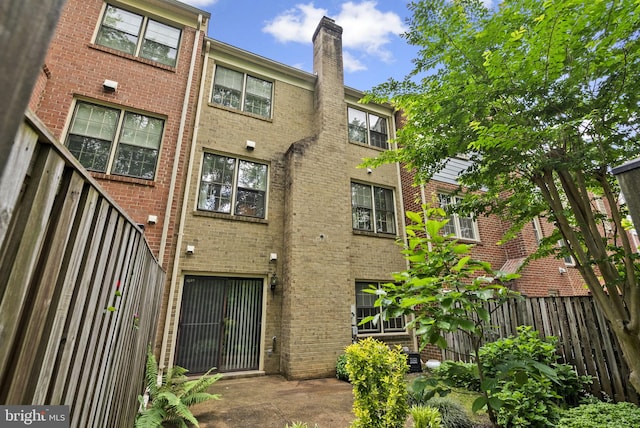 4849 Carriagepark Rd, Fairfax, VA 22032 - rear view of property featuring brick siding, fence, and a chimney