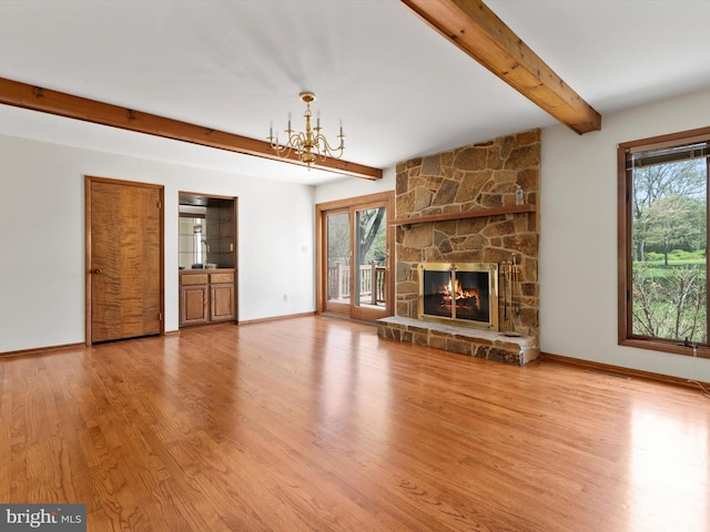 unfurnished living room with beam ceiling, a chandelier, wood finished floors, and plenty of natural light