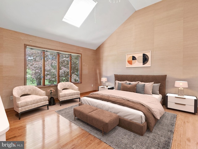 bedroom with a skylight, wood finished floors, wallpapered walls, and high vaulted ceiling