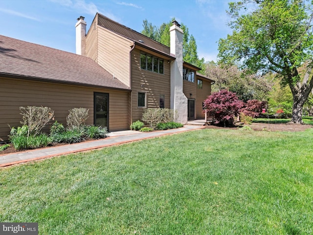 back of house with a chimney and a yard