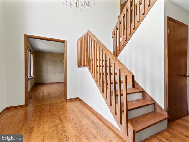 stairs with wood finished floors, baseboards, and a chandelier