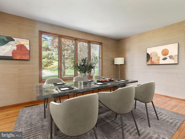 dining room featuring light wood finished floors, baseboards, healthy amount of natural light, an office area, and wallpapered walls