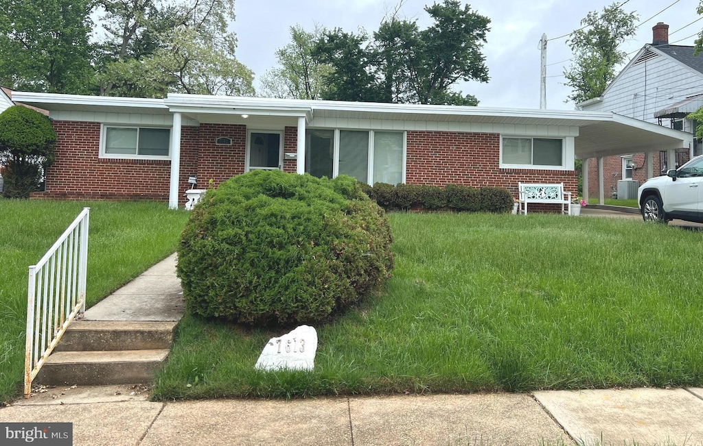 view of front of house with brick siding, a front yard, and an attached carport