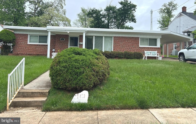 view of front of house with brick siding, a front yard, and an attached carport