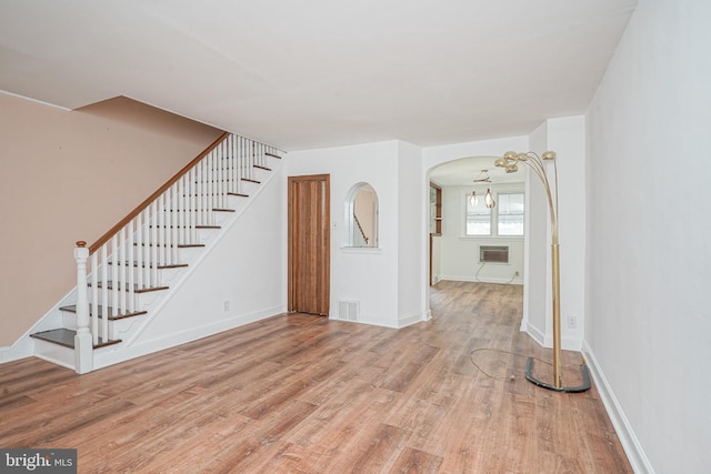 3311 Meridian St, Philadelphia, PA 19136 - unfurnished living room with wood finished floors, stairs, an AC wall unit, arched walkways, and baseboards