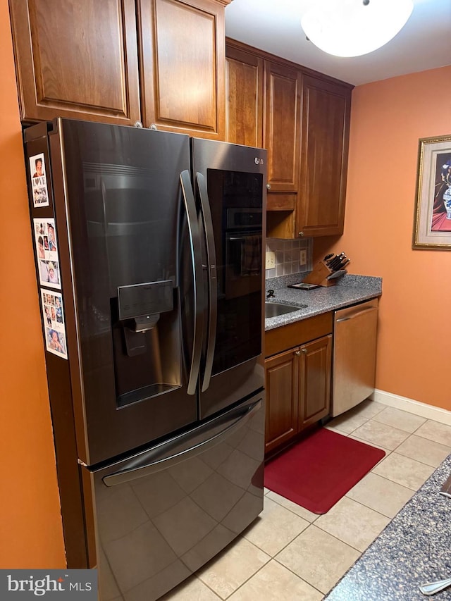 1250 S Washington St S Unit 207, Alexandria, VA 22314 - kitchen featuring appliances with stainless steel finishes, light tile patterned floors, brown cabinets, and baseboards