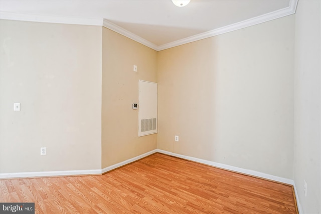 empty room with ornamental molding, wood finished floors, and baseboards