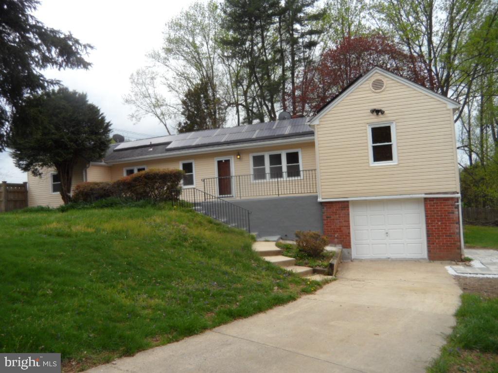 view of front of property with solar panels, a garage, a front yard, and driveway