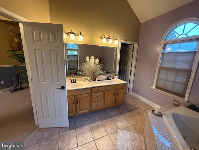 15920 River Bend Ct, Williamsport, MD 21795 - bathroom with tile patterned flooring, double vanity, tiled bath, high vaulted ceiling, and baseboards