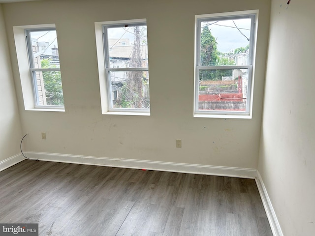unfurnished room with wood finished floors, baseboards, and healthy amount of natural light