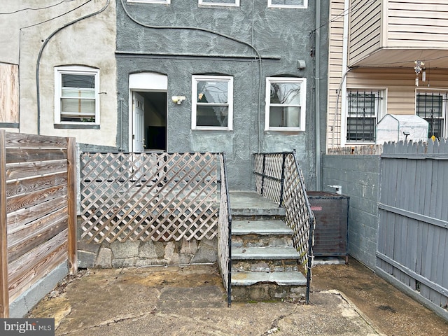 doorway to property featuring fence and stucco siding