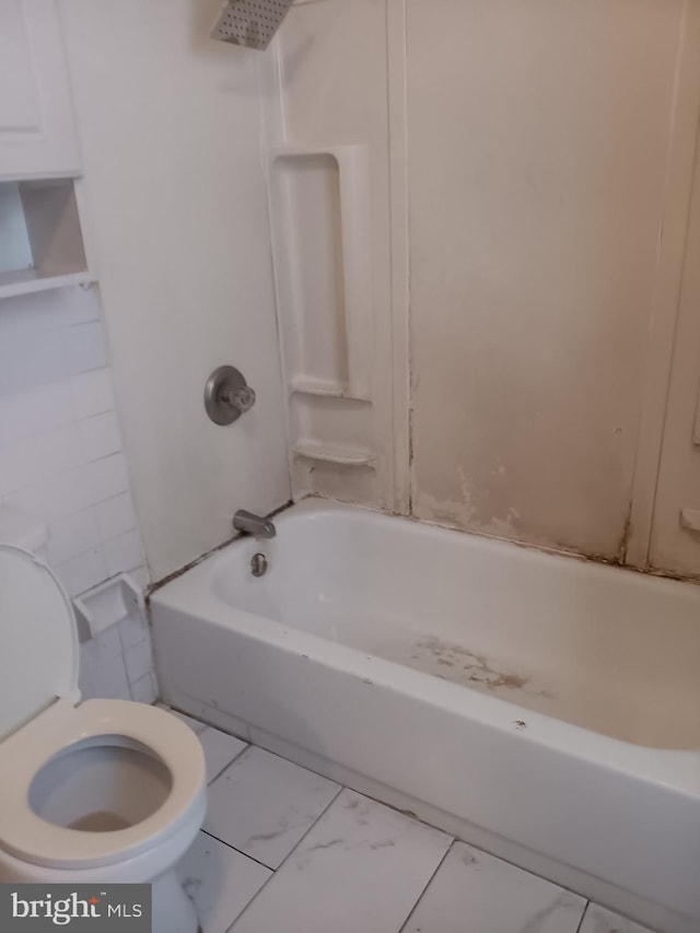 full bath with toilet, marble look tile flooring, and tub / shower combination