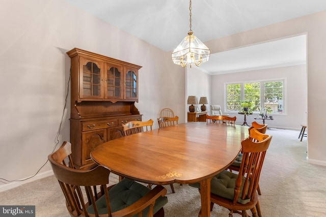 dining room featuring a chandelier, light carpet, and baseboards