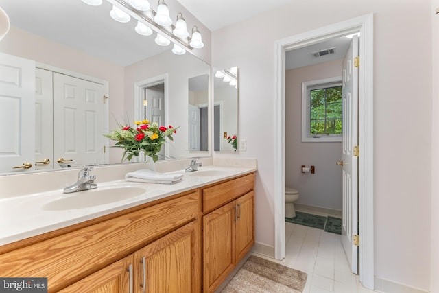 full bathroom with toilet, tile patterned floors, double vanity, and baseboards