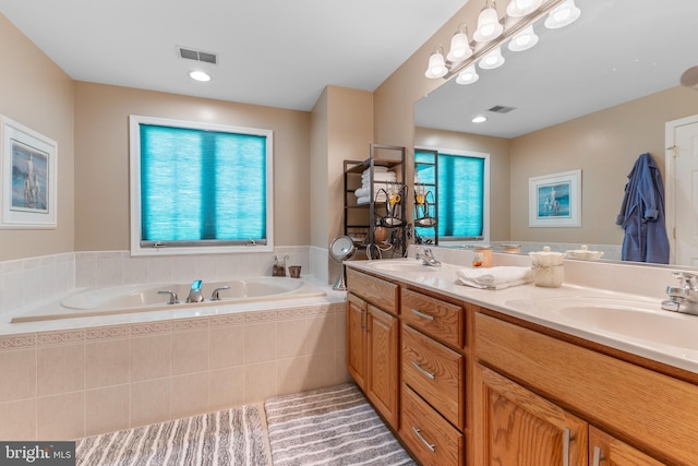 full bathroom featuring plenty of natural light, a bath, and double vanity