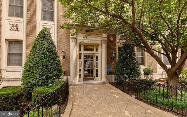 view of exterior entry with brick siding and fence