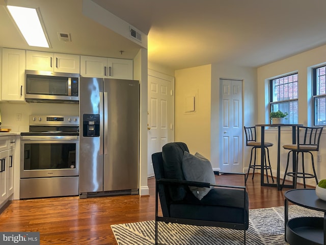 kitchen with appliances with stainless steel finishes, dark wood finished floors, white cabinetry, and light countertops