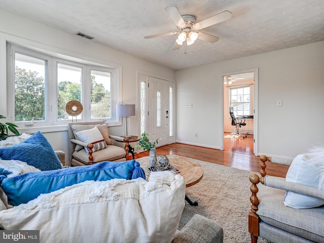 living room with a ceiling fan, wood finished floors, a textured ceiling, and baseboards