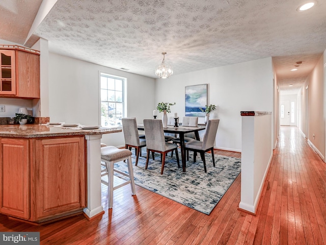 dining area featuring light wood-type flooring, baseboards, a chandelier, a textured ceiling, and recessed lighting